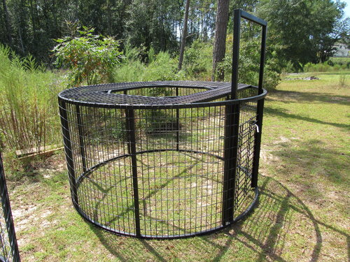 A large metal cage with trees in the background.